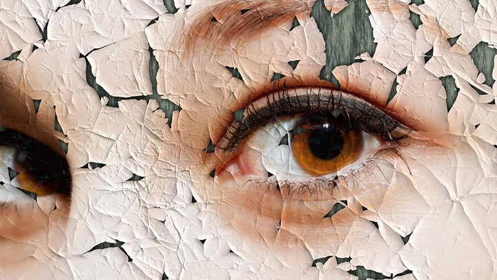 A close-up of a woman's beautiful brown eyes on an old oil painting that is cracking and pealing